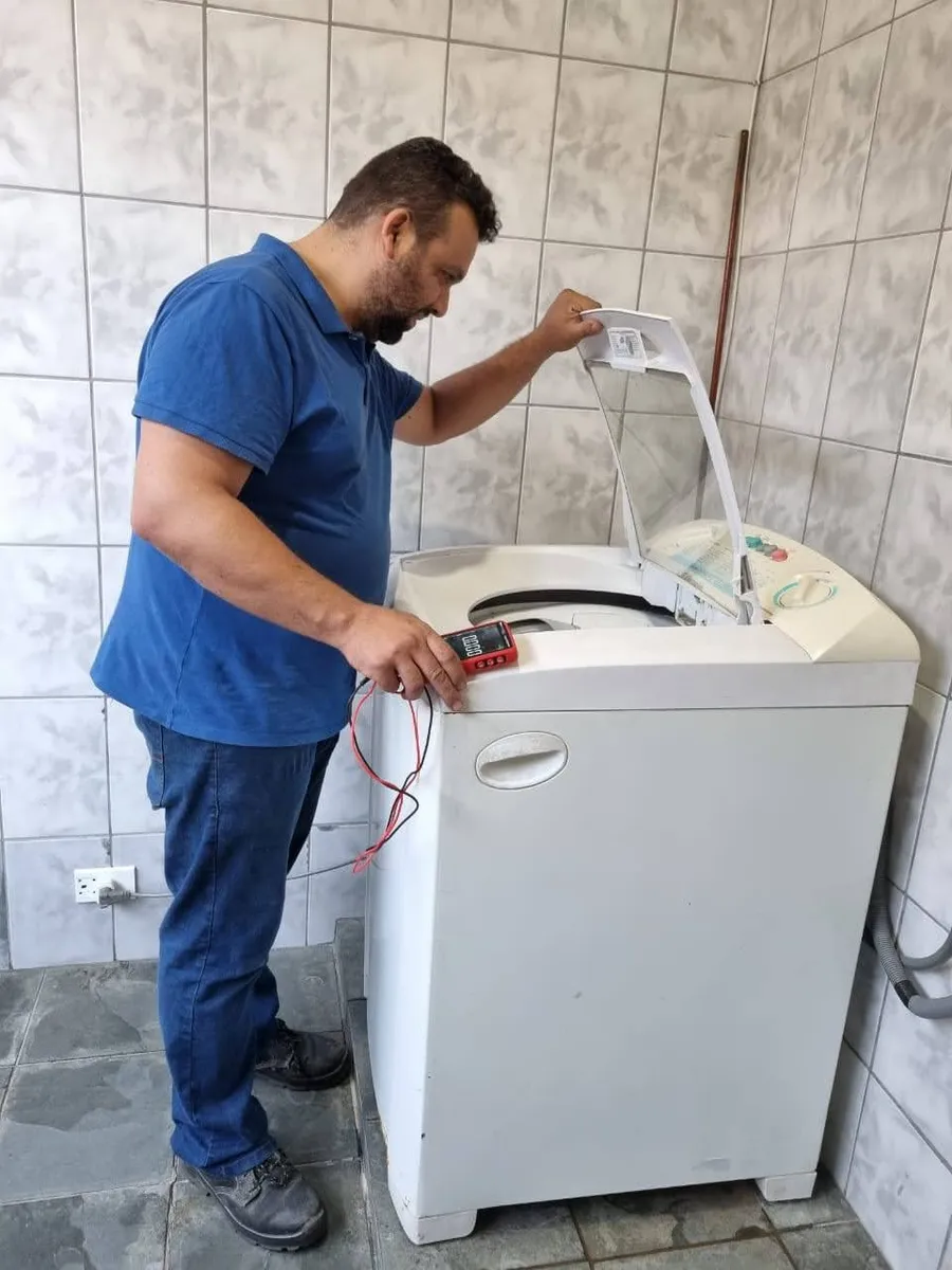 Man pouring liquid detergent into a stacked washer and dryer in a modern laundry room.